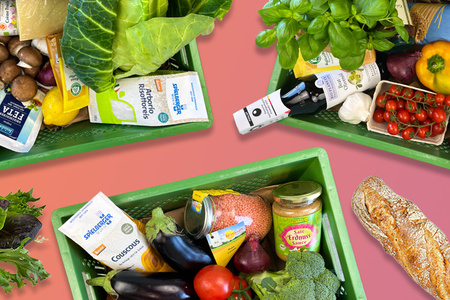 Drei grüne Kisten mit frischem Obst, Gemüse und Lebensmitteln auf pinkem Hintergrund.