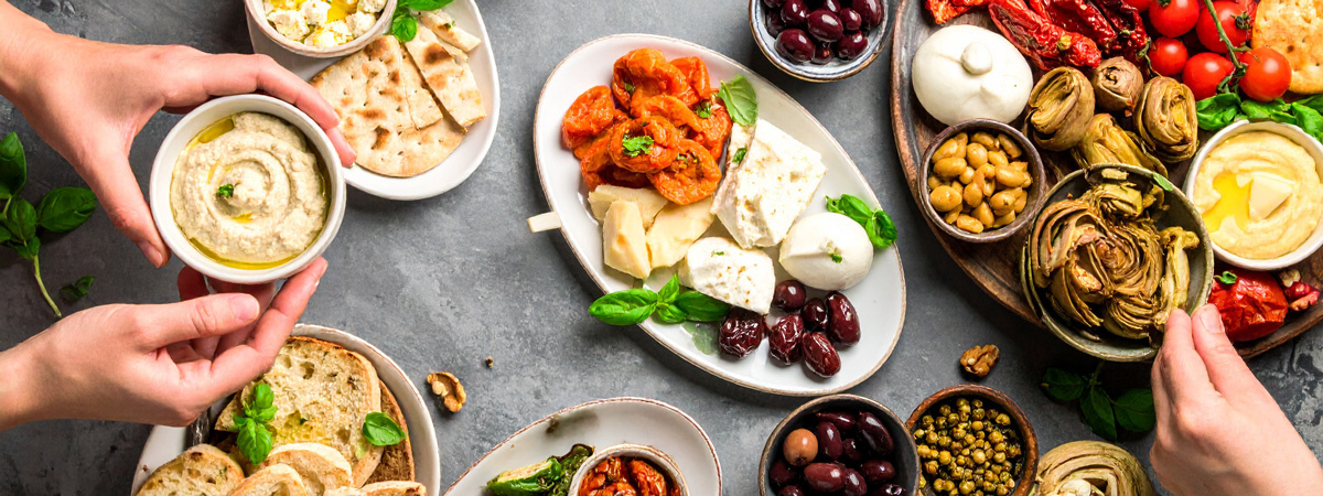 KI generiert: Ein Tisch voller mediterraner Vorspeisen, darunter Käse, Oliven, Hummus und eingelegtes Gemüse.