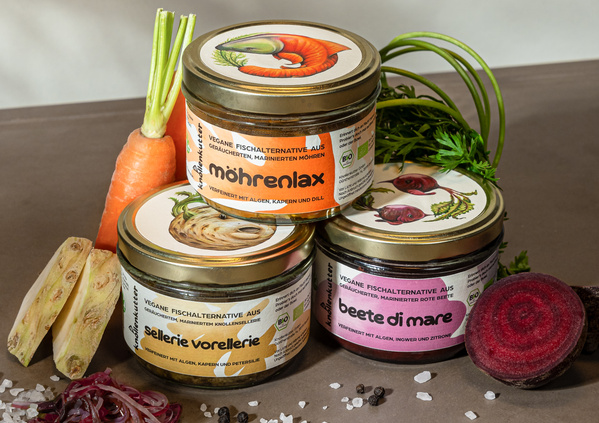 KI generiert: Drei Gläser mit veganen Fischalternativen aus Gemüse: "möhrenlax," "s­ellerie forellerie," und "beete di mare".