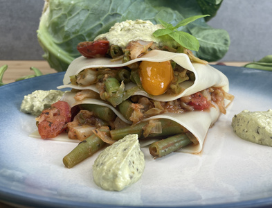 Gefüllte Zucchini in Pfanne mit Kartoffeln und Petersilie, umgeben von frischem Gemüse und Käse.