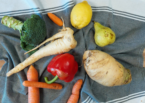 KI generiert: Verschiedenes Gemüse und Obst auf einem Tuch, darunter Brokkoli, Karotte, Paprika, Pastinake, Zitrone und Birne.