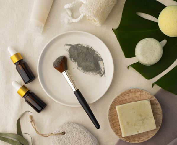 KI generiert: Naturkosmetik: Pinsel, Tonpulver, ätherische Öle, Seife, Schwamm auf einem hellen Hintergrund.