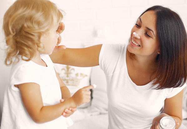 KI generiert: Eine Frau und ein Kind spielen lachend mit Gesichtscreme.