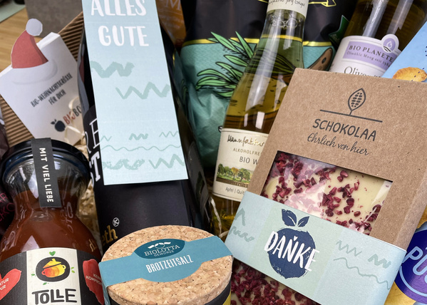 KI generiert: Geschenkset mit verschiedenen Bio-Produkten, darunter Schokolade und Brotzeitsalz. Text: "ALLES GUTE", "DANKE".