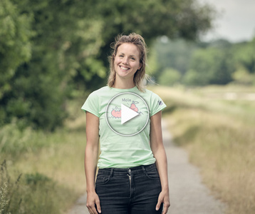 Gründerin Lisa steht lächelnd auf einem ländlichen Weg. Text auf dem Shirt: "Moin" mit einer Tomate.