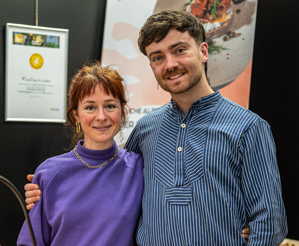 KI generiert: Zwei Personen posieren lächelnd vor einer Tafel mit Auszeichnung oder Werbeplakat.