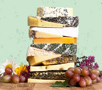 Ein Stapel verschiedener Käsesorten mit Blumen und Trauben.