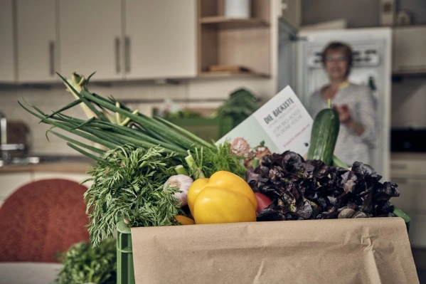 KI generiert: Eine Kiste mit frischem Gemüse und ein unscharfer Hintergrund. Text: "DIE GEMÜSEKISTE".