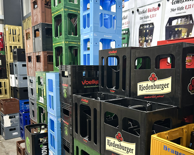 KI generiert: Gestapelte Getränkekisten verschiedener Marken. Text: "Voelkel" und "Riedenburger".