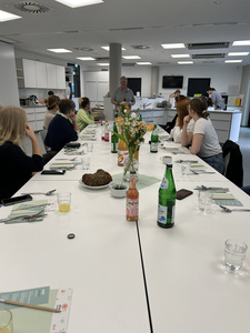 Eine Gruppe von Menschen sitzt um einen Tisch in einer modernen Küche.