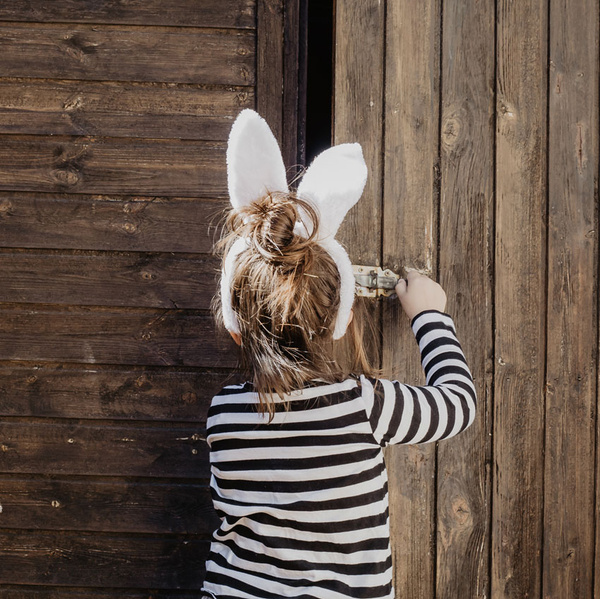 KI generiert: Ein Kind mit Hasenohren öffnet eine Holztür.