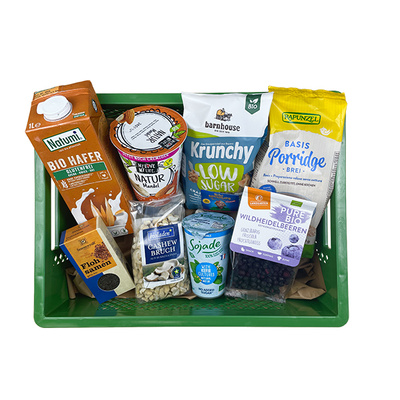 KI generiert: Grüne Kiste mit verschiedenen Bio-Lebensmitteln, darunter Haferdrink und Porridge.