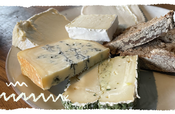 KI generiert: Eine Platte mit verschiedenen Käsesorten und Brotscheiben.