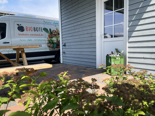 KI generiert: Ein Lieferwagen mit der Aufschrift "BIOBOTE" steht vor einem Haus. Text auf dem Wagen: "biobote-emsland.de".