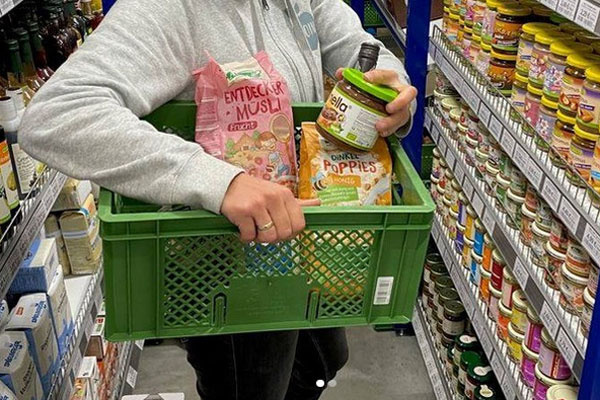 Bioboten Angestellteträgt einen grünen Biokiste mit Müsli und Bio-Produkten im Supermarkt.