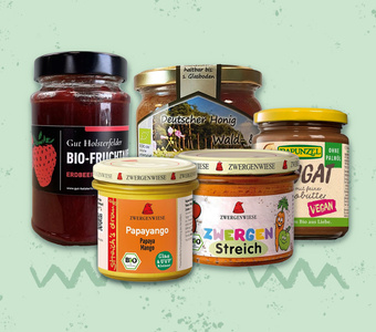Verschiedene Bio- und vegane Aufstriche, darunter Erdbeerkonfitüre, Honig und Nuss-Nougat-Creme.