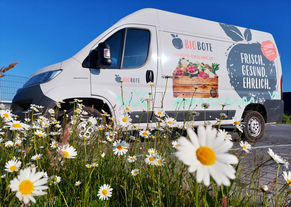KI generiert: Ein Lieferwagen mit der Aufschrift "BIO BOTE. Frisch. Gesund. Ehrlich." steht auf einem Parkplatz.