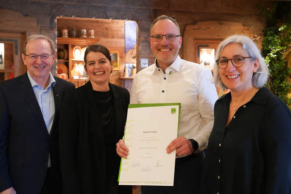 KI generiert: Vier Personen posieren lächelnd mit einem Diplom. Text darauf: "Andreas Arting - Diplomierter Kräuterpädagoge".