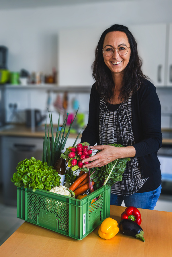 junge Frau packt Biokiste aus