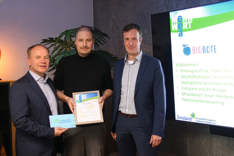 KI generiert: Drei Männer bei einer Auszeichnung, Präsentation über Nachhaltigkeit von "Biobote" auf Monitor.