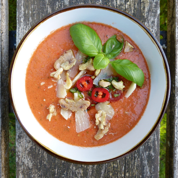 KI generiert: Ein Teller Suppe mit Basilikum, Walnüssen, Zwiebeln und Chili auf Holzuntergrund.