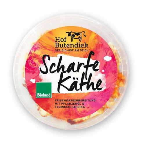 KI generiert: Das Bild zeigt eine Verpackung von "Scharfe Käthe", einem Frischkäseprodukt von Hof Butendiek, mit pflanzlichem Öl und feurigem Paprika, zertifiziert durch Bioland. Die Gestaltung ist bunt und auffällig, um die scharfe Geschmacksrichtung zu betonen.