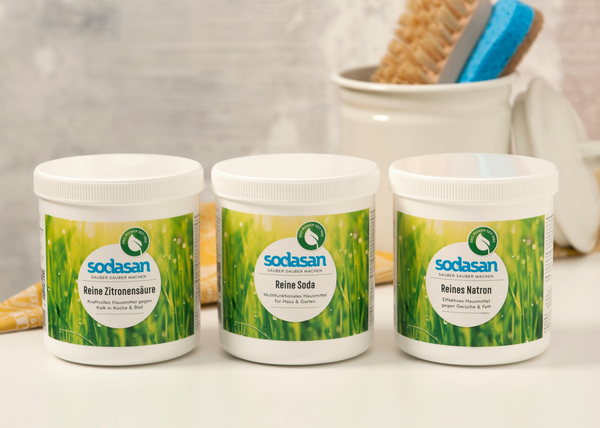 KI generiert: Drei Behälter mit umweltfreundlichen Reinigungsmitteln von Sodasan. Text: "Reine Zitronensäure", "Reine Soda", "Reines Natron".