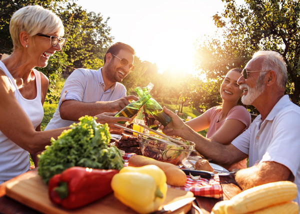 Vierköpfige Familie draußen, Salat, gemüse, anstoßen mit Bier
