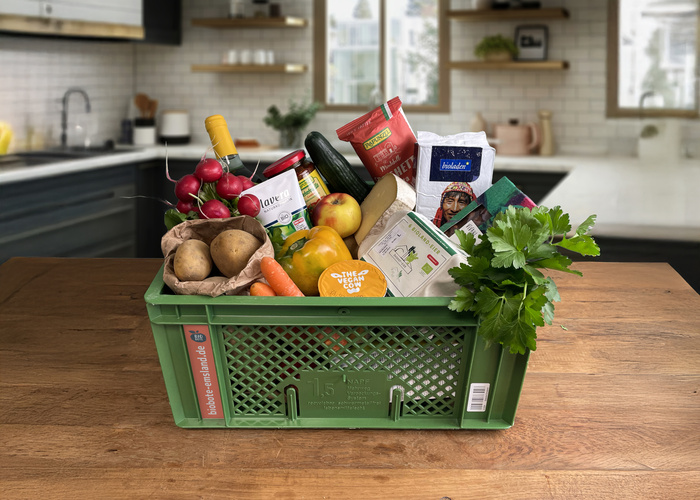 KI generiert: Ein grüner Korb voller Gemüse und Lebensmittel steht in einer Küche. Text: "bioober-erland.de".