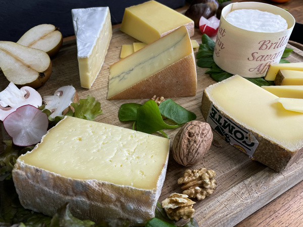 KI generiert: Auf dem Bild sind verschiedene Käsesorten auf einem Holzbrett arrangiert, umgeben von Walnüssen, Birnen, Radieschen und Salatblättern. Der Hauptinhalt des Bildes ist eine ansprechende Käseplatte, die mit frischen Zutaten dekoriert ist.